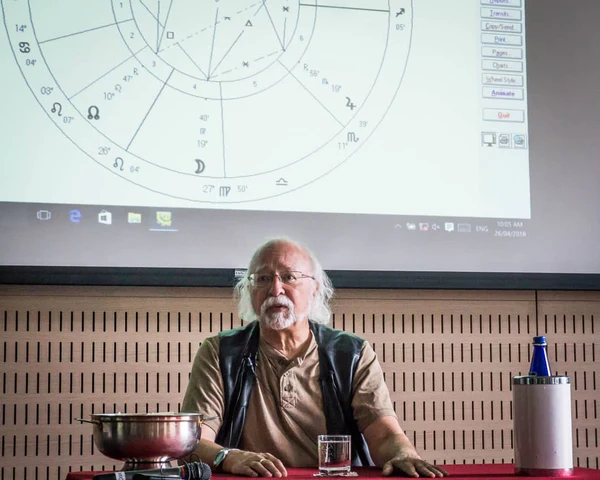 Steven Forrest teaching beneath a projected astrological chart